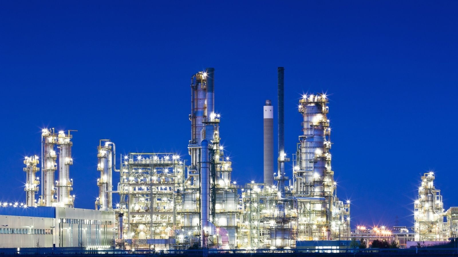 A large refining and processing complex illuminated at night. BP's February 2025 reset capped total capital expenditure at 13 to 15 billion US dollars a year through 2027 while raising oil and gas investment to around 10 billion.