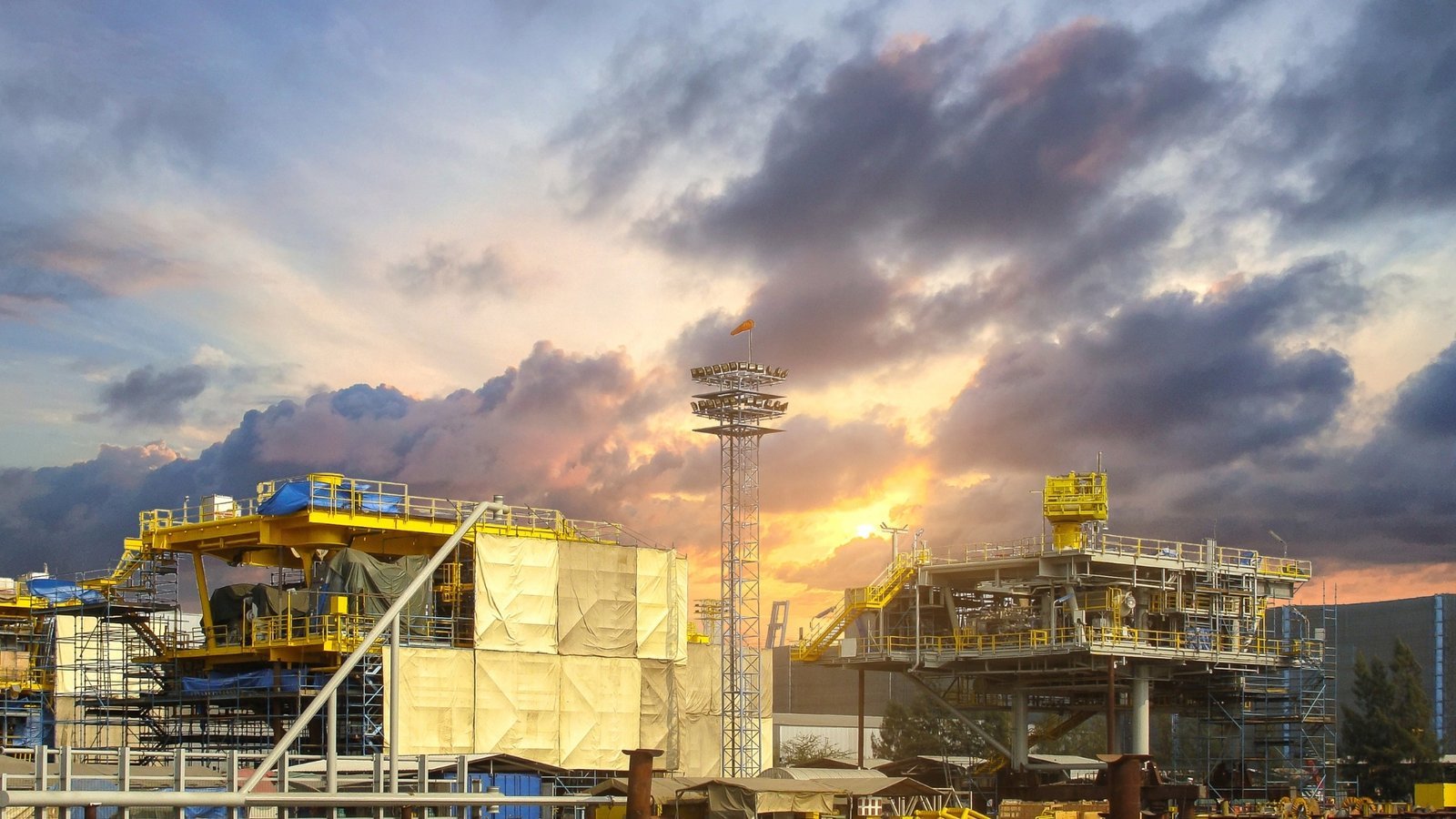An industrial energy construction yard at dusk with fabrication modules and floodlights