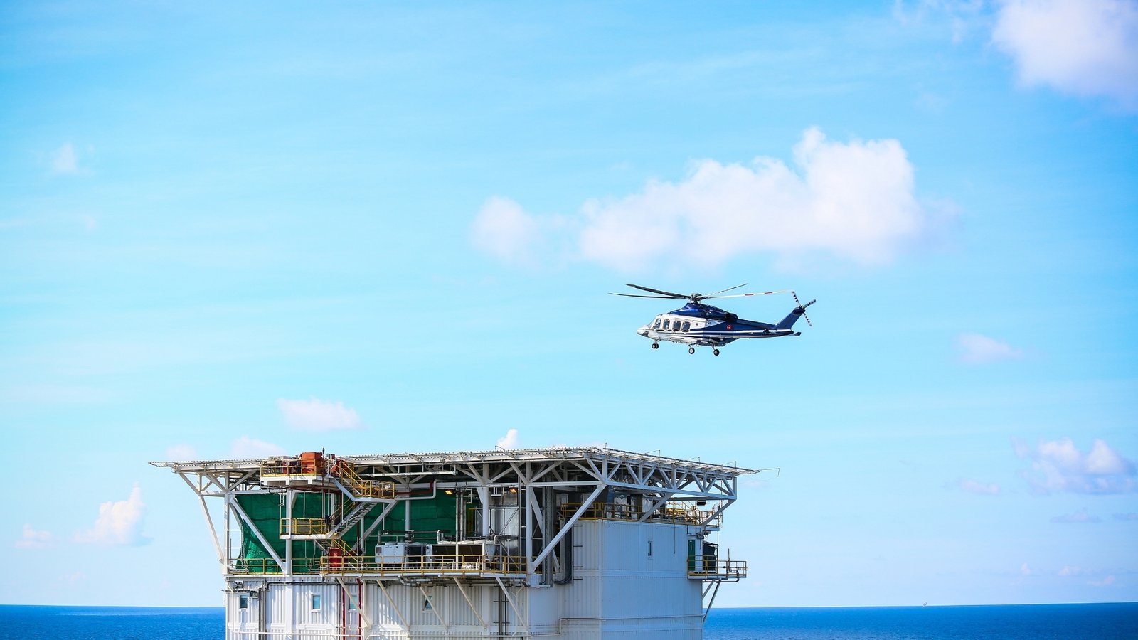 A helicopter approaches an offshore production platform above open sea